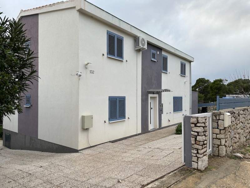 Fasada domu z wejściem i miejscem parkingowym na ogrodzonej posesji w Chorwacji