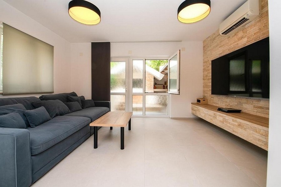 Nowoczesny salon z sofą, ścianą telewizyjną i wyjściem na taras
