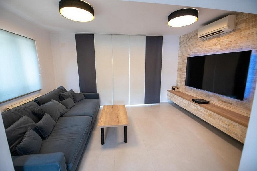 Pokój dzienny z dużą powierzchnią telewizyjną i nowoczesnym designem ścian
