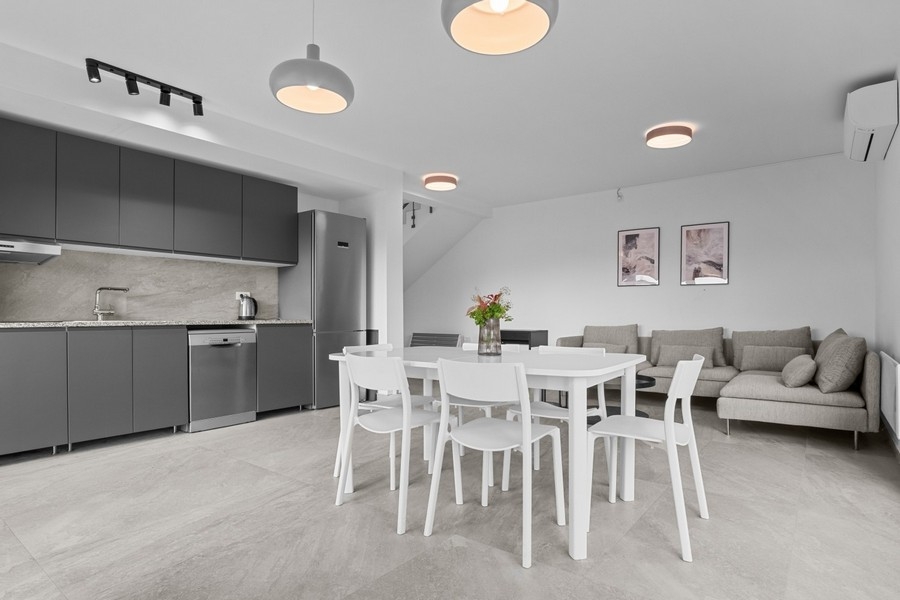 Jasny salon z sofą i zintegrowaną kuchnią na otwartym planie