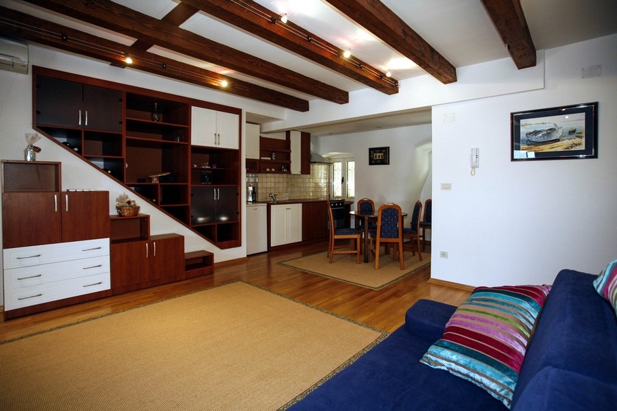 Część dzienna z otwartą kuchnią i odsłoniętymi drewnianymi belkami stropowymi