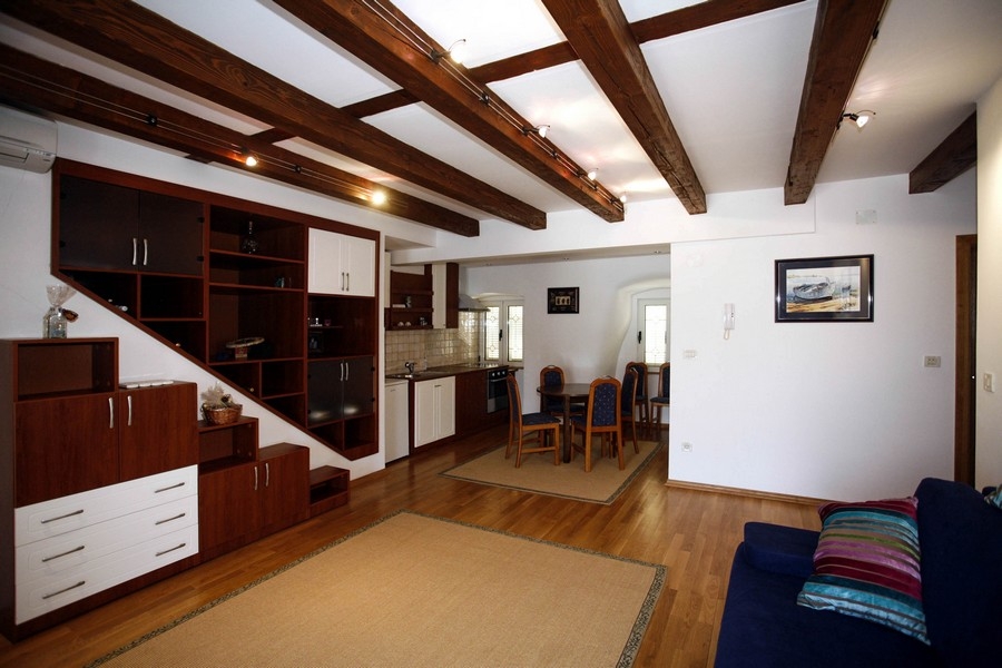 Otwarty salon z wyposażoną kuchnią i drewnianym sufitem