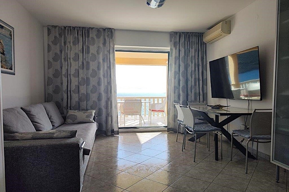 Pokój dzienny z wyjściem na balkon i widokiem na morze
