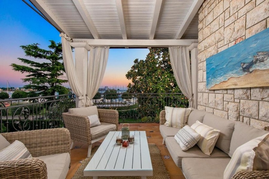 Balkon z meblami wypoczynkowymi i widokiem na morze o zachodzie słońca