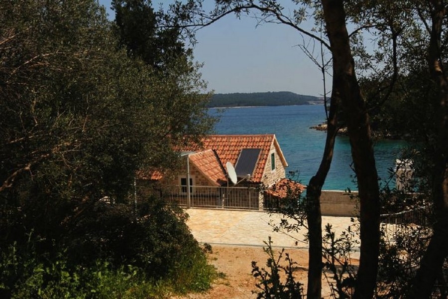 Kamienny dom z widokiem na morze między drzewami