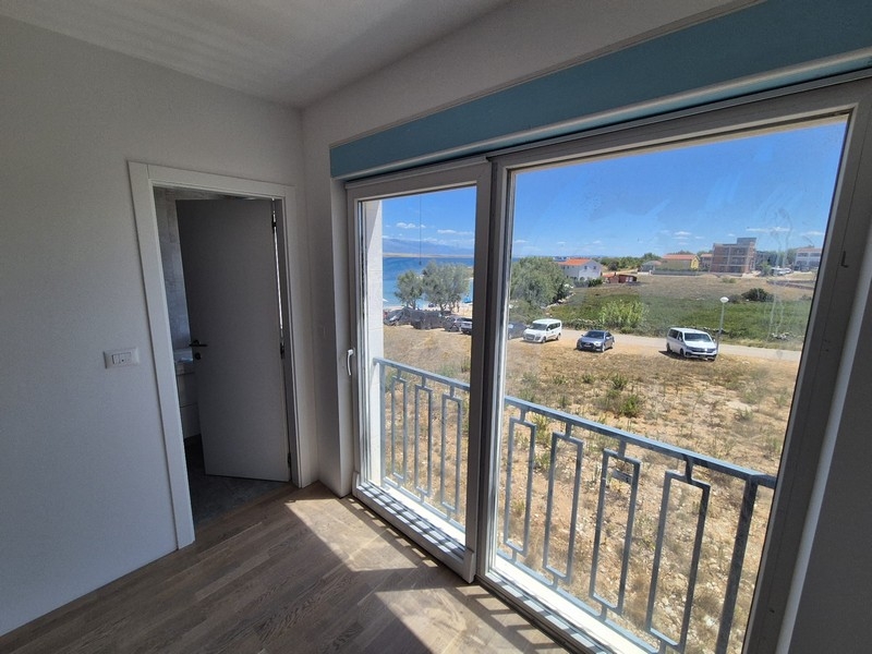 Sypialnia z dużymi oknami i wyjściem na balkon z widokiem na morze.