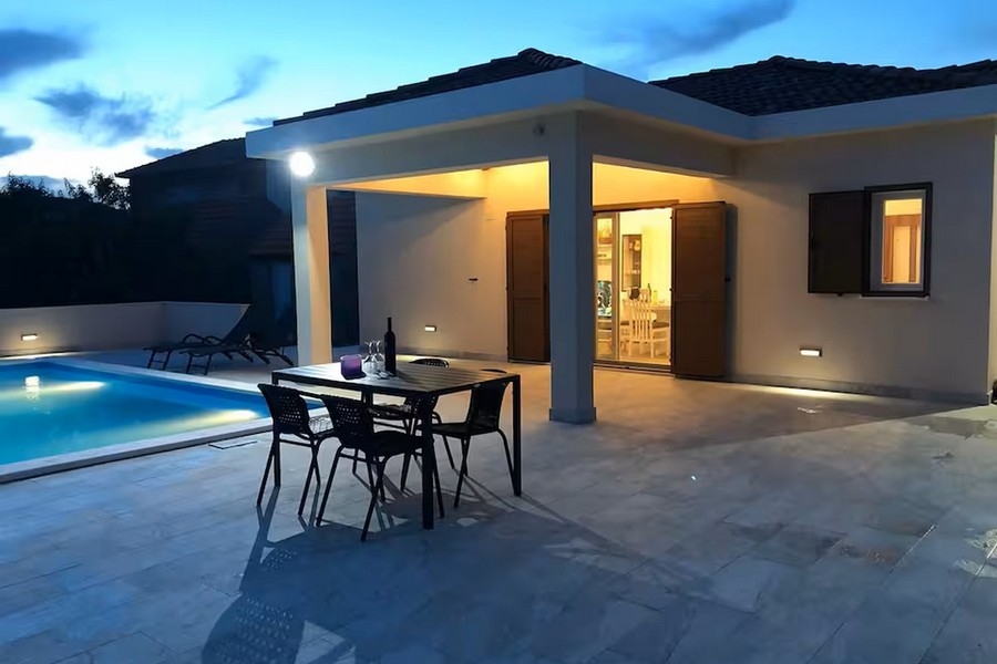 Bungalow wieczorem z basenem i zadaszonym tarasem