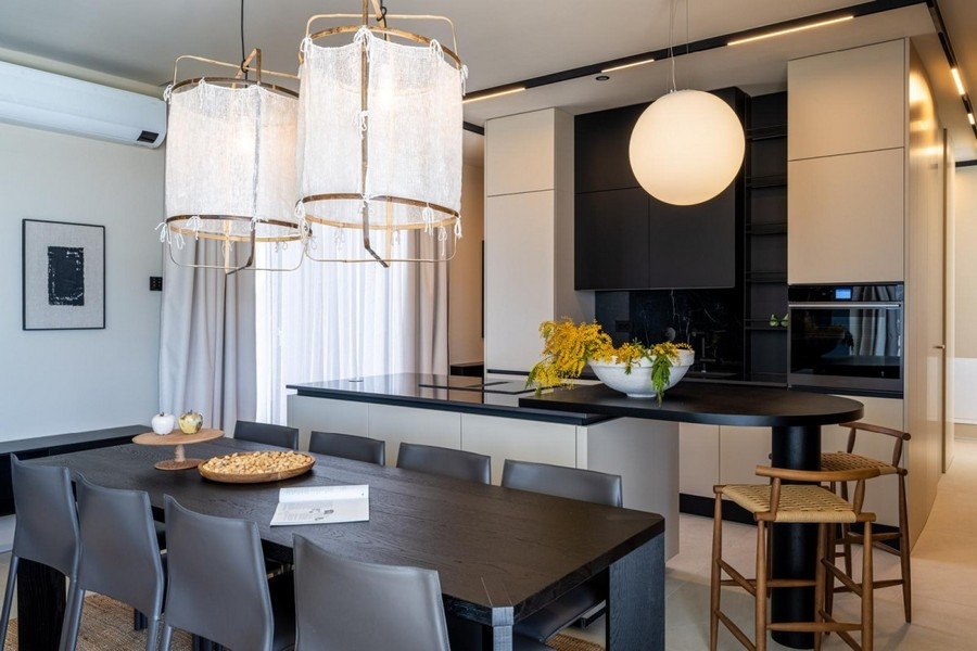 Stół jadalny z designerskimi lampami przed otwartą kuchnią
