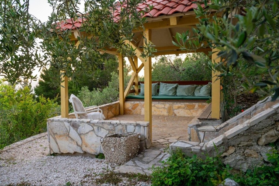 Pergola z ławką między drzewami oliwnymi