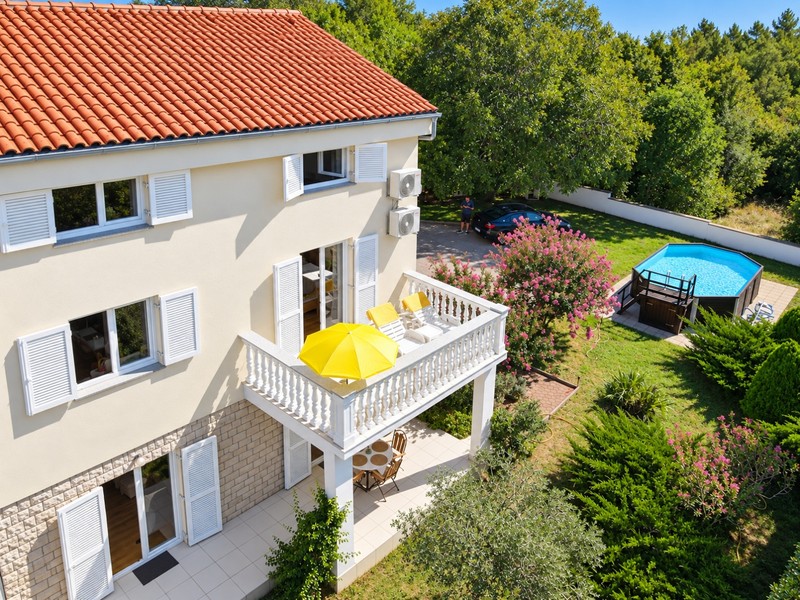 Balkon z leżakami nad ogrodem z basenem