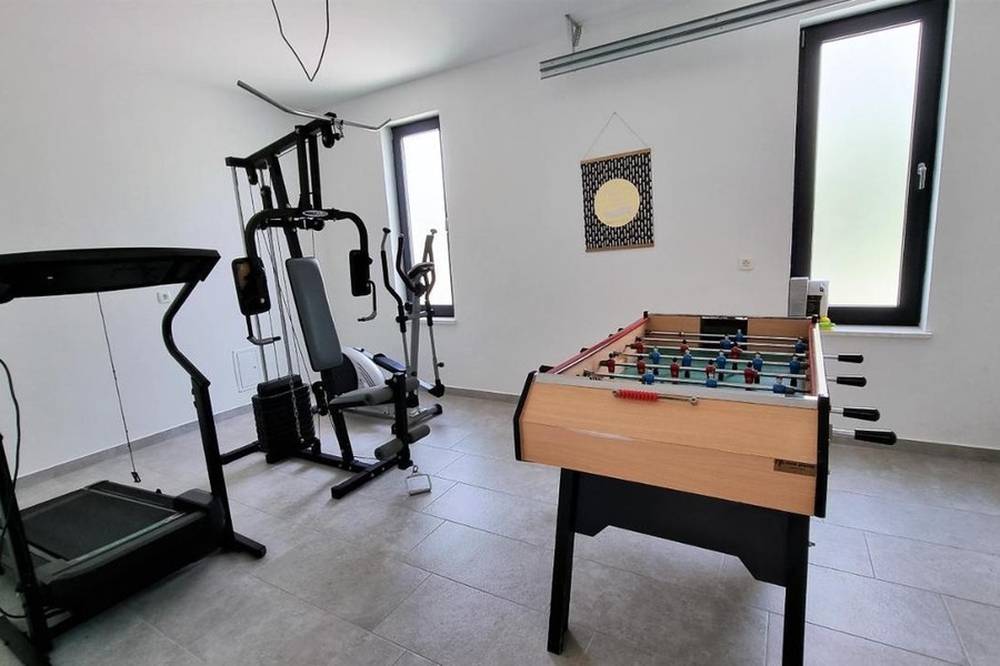 Pomieszczenie z urządzeniami fitness i stołem do piłkarzyków